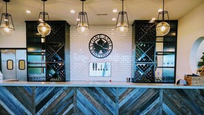 A bar area with a herringbone-patterned countertop, wine racks, and pendant lighting.