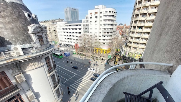 A high-rise building with a view of a busy street below, featuring a mix of modern and older architecture. - amzei square Apt (Bucharest)