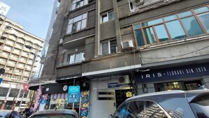 A multi-story building with balconies, a storefront with a sign, and parked cars. - amzei square Apt (Bucharest)
