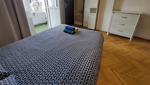 A bedroom with a patterned bedspread, a wardrobe, and a window with curtains. - amzei square Apt (Bucharest)