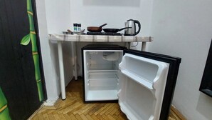 A compact kitchen with a refrigerator, a microwave, and a kettle on a small countertop. - amzei square Apt (Bucharest)