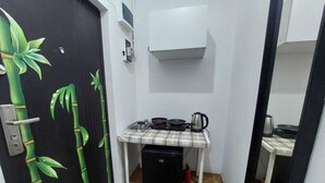 A small kitchenette with a microwave, kettle, and frying pan on a table. - amzei square Apt (Bucharest)