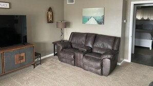A living room with a leather sofa, a television, a small table, and a picture frame on the wall. - Spacious 2-bedroom condo with AC, WiFi in beautiful Osage Beach (Osage Beach)