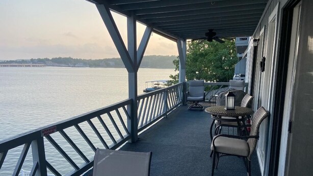 A covered deck with a view of the water, featuring outdoor seating and a caution sign. - Spacious 2-bedroom condo with AC, WiFi in beautiful Osage Beach (Osage Beach)