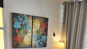 Ein Wohnzimmer mit einem grauen Ecksofa, einem blauen Teppich mit Muster und einem farbenfrohen abstrakten Gemälde an der Wand.