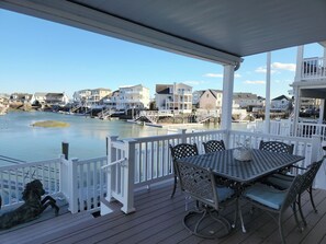 A covered deck with a table and chairs, overlooking a waterfront with houses and a small island. - 4-bedroom waterfront house in wonderful Avalon (Avalon)