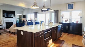 Une cuisine moderne dotée d’un grand îlot central, de meubles en bois foncé et de luminaires suspendus.