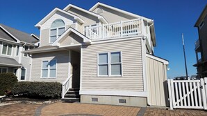 Une maison à deux étages avec un porche à l’avant, un garage et une allée menant à une porte.