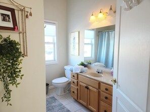 A bathroom with a toilet, sink, and mirror. There is a plant on the left and a window above the toilet. - 4-bedroom waterfront house in wonderful Avalon (Avalon)