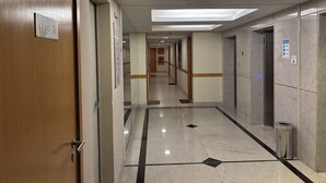 A hotel corridor with a wooden door on the left, a sign indicating the exit, and a trash can on the right. - Loft with pool - Near Riocentro and Barra (Rio de Janeiro)