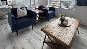 A modern living room with a large window, a ceiling fan, a flat-screen TV, and a wooden coffee table. - Downtown Suite - Stunning View Right in the centre of Edmonton (Edmonton)
