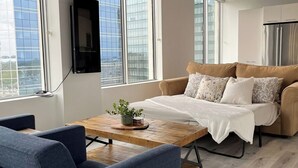 A modern living room with a sofa, a coffee table, and a TV mounted on the wall. - Downtown Suite - Stunning View Right in the centre of Edmonton (Edmonton)