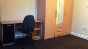 A room with a wooden desk, black office chair, and a large wardrobe with a mirror. - Bradford 2-bedroom Home - Sleeps 4 - Free Parking (Bradford)
