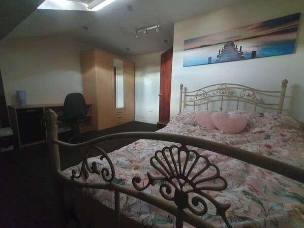 A bedroom with a bed, a desk, and a wardrobe.