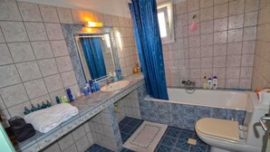 A bathroom with a sink, mirror, bathtub, and toilet.