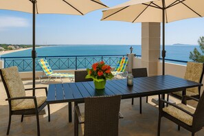 A terrace with a table, chairs, and umbrellas overlooking a beach and sea. - La Casa di Anastasia Panorama 2 on the Sea (Nea Karvali)