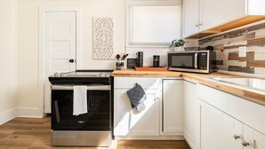 A kitchen with a built-in oven, microwave, and wooden countertop.