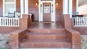 A front porch with steps leading to a door, a bench, and a table.
