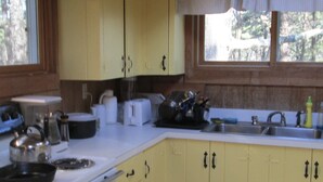 Una cocina con gabinetes amarillos, una estufa, un fregadero y varios electrodomésticos.