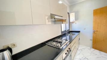 A modern kitchen with white cabinets, a black countertop, a gas stove, and a built-in oven.