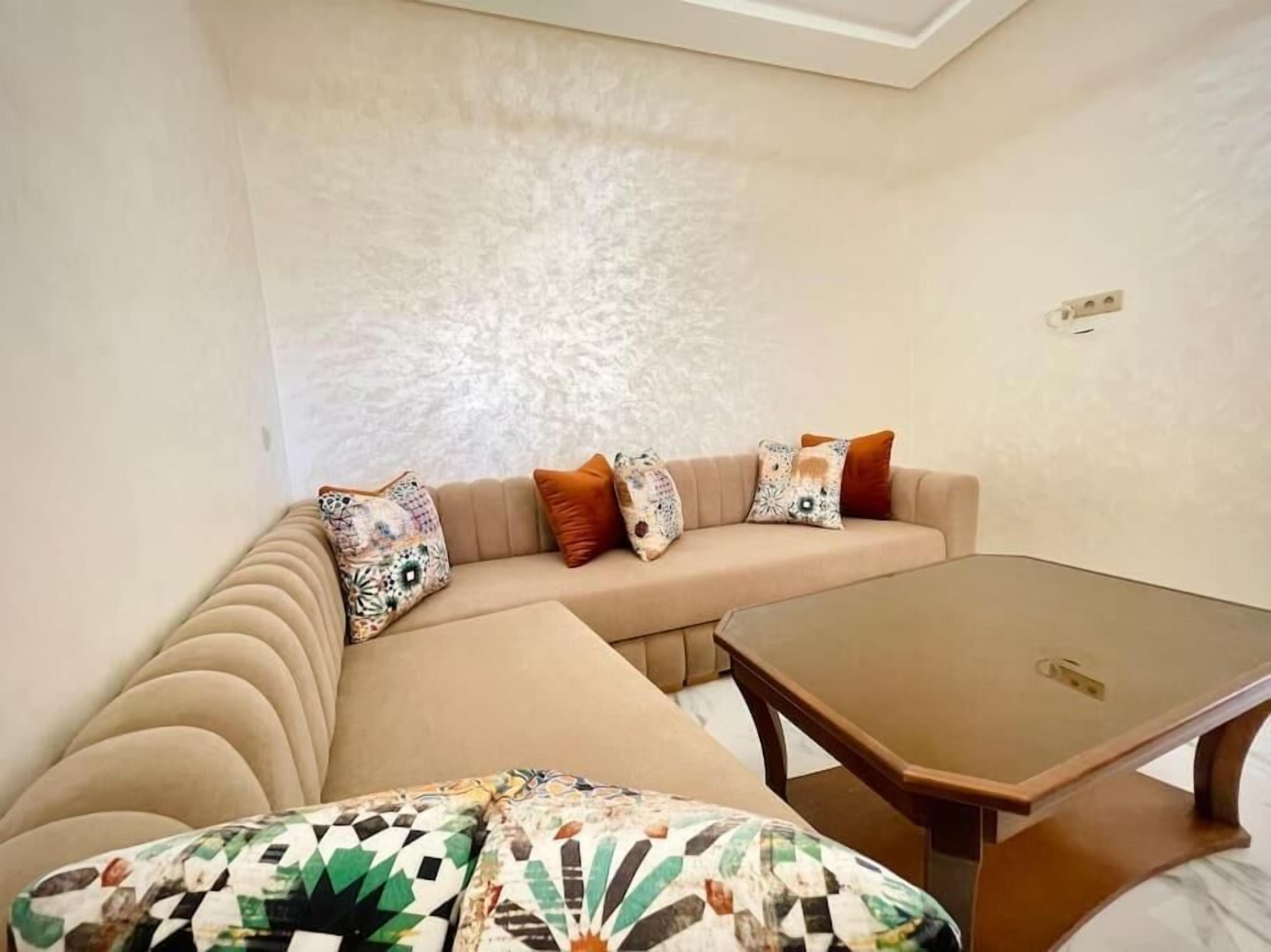 Una sala de estar moderna con un sofá color beige, cojines estampados y una mesa de centro de madera.