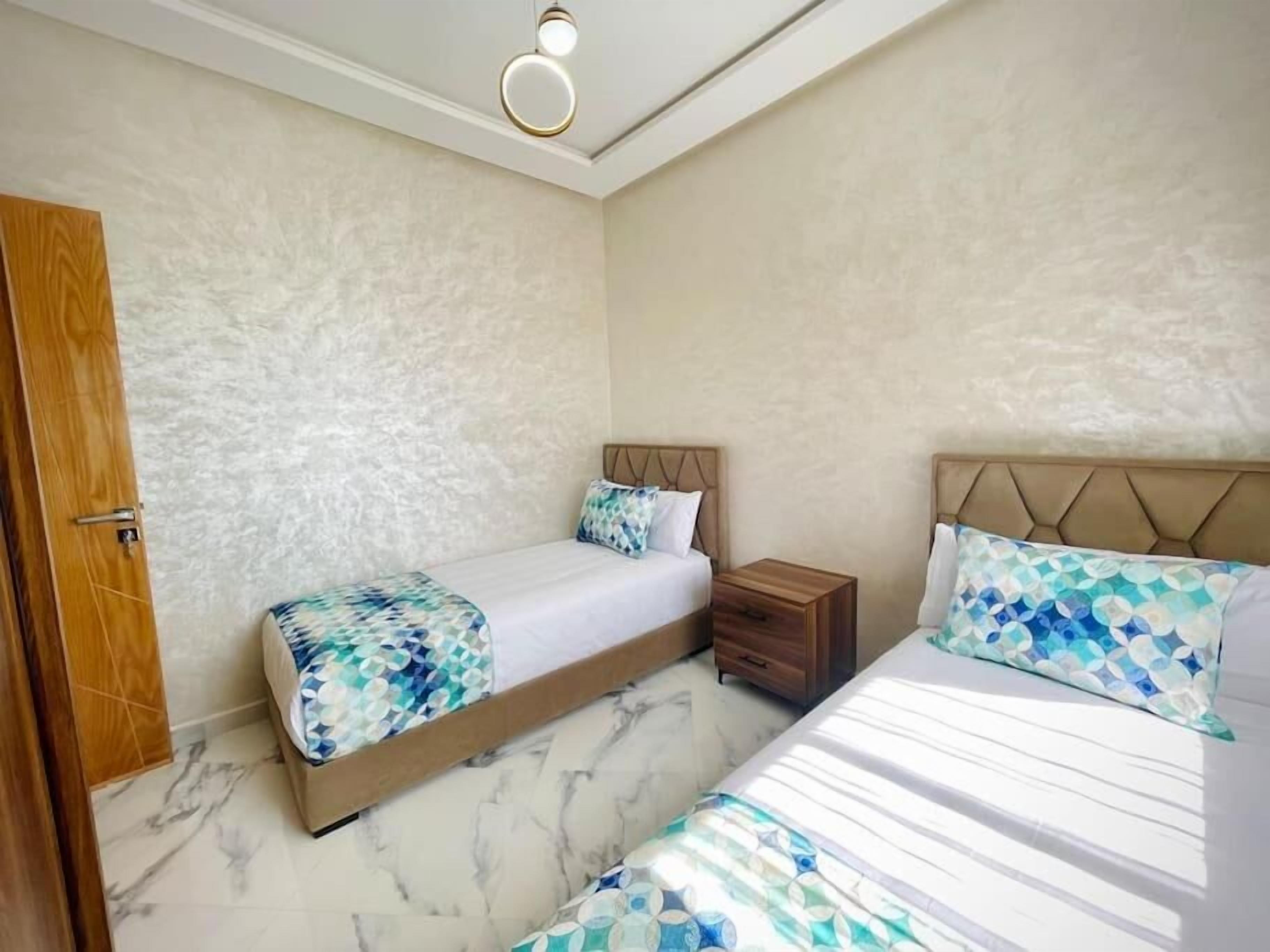 Un dormitorio con dos camas, una mesita de noche de madera y suelo de mármol.