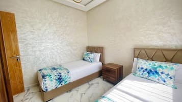 Un dormitorio con dos camas, una mesita de noche de madera y suelo de mármol.