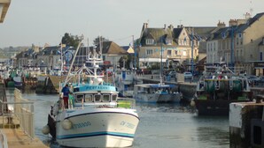 A harbor with boats docked, buildings in the background, and a clear sky. - Vacation home in Normandy (Aure sur Mer)