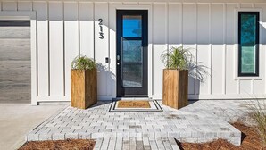 A modern house with a black door, white siding, and a number '213' above the door. - Talulah Sunrise (Panama City Beach)