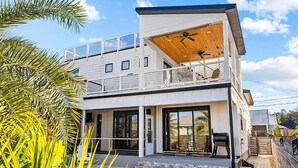 A modern two-story house with a large balcony, a swimming pool, and a wooden deck. - Talulah Sunrise (Panama City Beach)