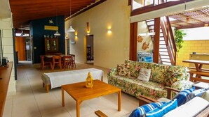 A spacious living area with a wooden coffee table, a floral sofa, and a dining table with chairs. - Casa c Wi-fi Jacuzzi e Churrasqueira em Guaec SP (São Sebastião)