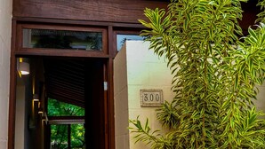 A building entrance with a wooden door, a number sign '300', and a large green plant on the right. - Casa c Wi-fi Jacuzzi e Churrasqueira em Guaec SP (São Sebastião)