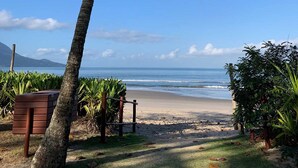 A beach with palm trees, a clear sky, and a view of the ocean. - Casa c Wi-fi Jacuzzi e Churrasqueira em Guaec SP (São Sebastião)