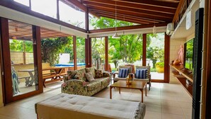 A spacious living area with a large bed, sofas, and a TV. - Casa c Wi-fi Jacuzzi e Churrasqueira em Guaec SP (São Sebastião)