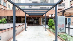 A covered outdoor area with a glass entrance, a sign for 'LONDON Residence Service 135', and a metal structure.