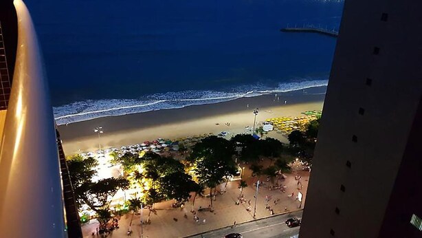 A beach view from a balcony with a view of the ocean and beachgoers. - Apto Beira-mar com Wi-fi e Piscina em Fortaleza (Fortaleza)