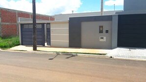 A modern building with a large garage door, a brick wall, and a concrete sidewalk. - Casa com Piscina e Wi-fi em Itapetininga (Itapetininga)