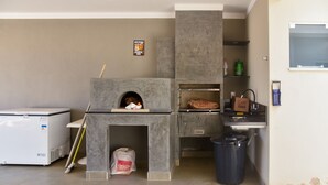 A kitchen with a built-in oven, a refrigerator, and a trash bin. - Casa com Piscina e Wi-fi em Itapetininga (Itapetininga)