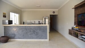 A modern kitchen with a marble island, a refrigerator, and a microwave. - Casa com Piscina e Wi-fi em Itapetininga (Itapetininga)
