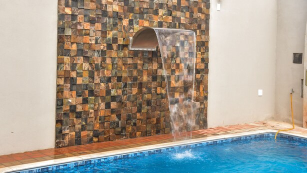 A swimming pool with a waterfall feature and a mosaic wall. - Casa com Piscina e Wi-fi em Itapetininga (Itapetininga)
