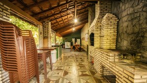 A rustic kitchen with a brick oven, wooden ceiling, and a patterned floor. - Pesqueiro - Rancho com Lazer Completo em Coxim MS (Coxim)