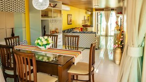 A dining area with wooden chairs, a glass table, and a colorful woven table runner. - Casa em Cond Fechado em Barra de Santo Ant nio AL (Barra de Santo Antonio)