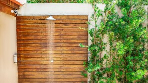 A wooden gate with a water feature, a white wall, and green foliage. - Casa em Cond Fechado em Barra de Santo Ant nio AL (Barra de Santo Antonio)