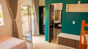 A room with a bed, a desk, and a bathroom visible through an open door. - Casa em Cond Fechado em Barra de Santo Ant nio AL (Barra de Santo Antonio)