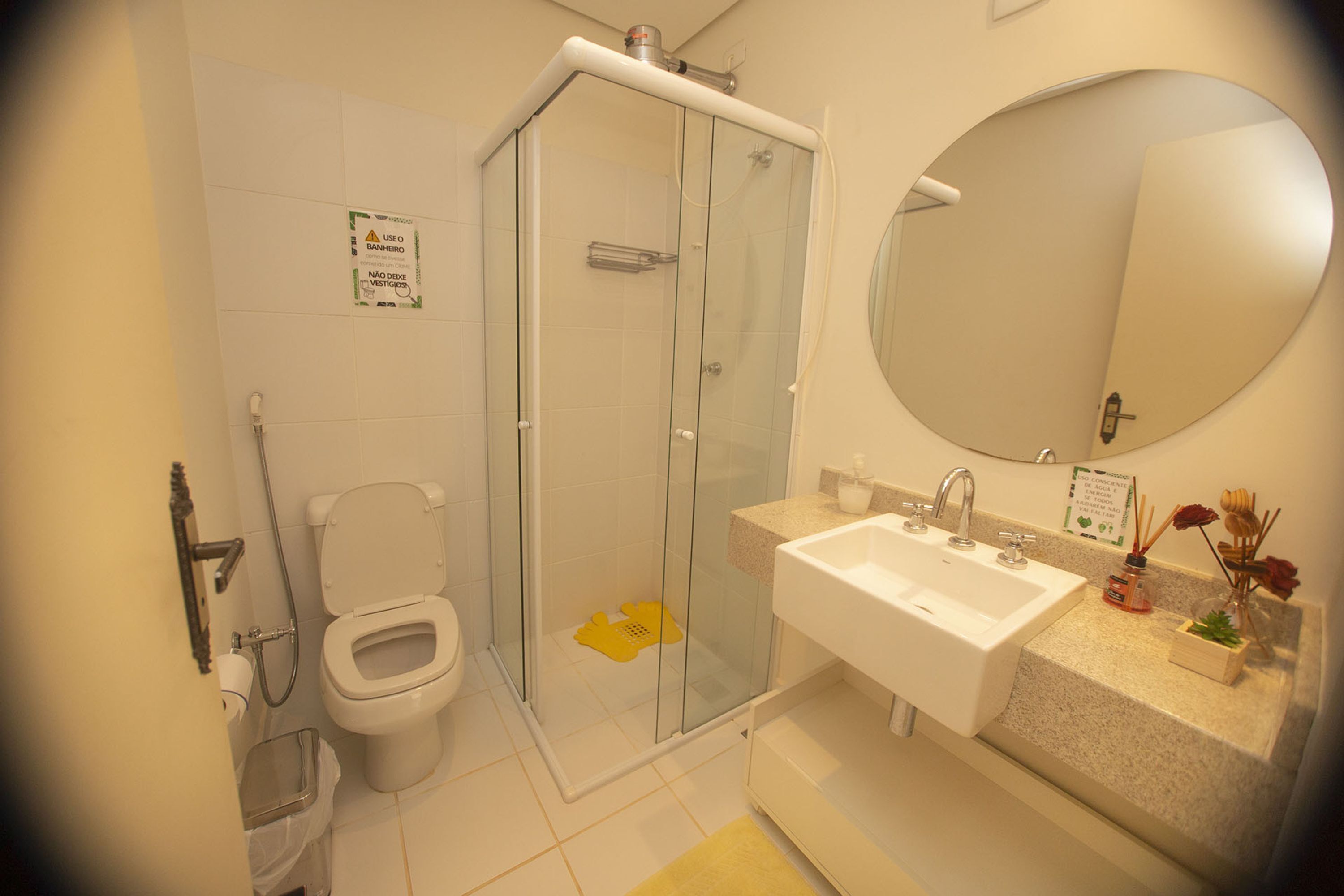 A bathroom with a toilet, shower, sink, and a large mirror.
