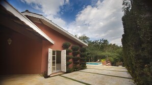 Ein Haus mit roter Fassade, einer weißen Tür und einem Steinweg, der zu einem Pool führt.
