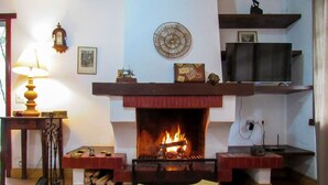 Un salon avec une cheminée, un téléviseur et une table décorée de bougies.