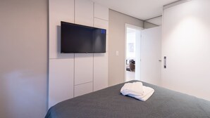 Une chambre d’hôtel moderne dotée d’un grand lit, d’un téléviseur à écran plat fixé au mur et d’une armoire aux portes coulissantes.