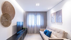 Un salon moderne avec un canapé, un téléviseur et des œuvres d’art décoratives au mur.