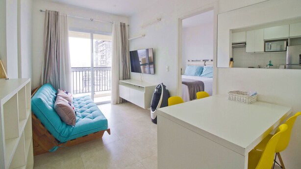 Una habitación de hotel moderna con cama, escritorio, silla, televisor y balcón.